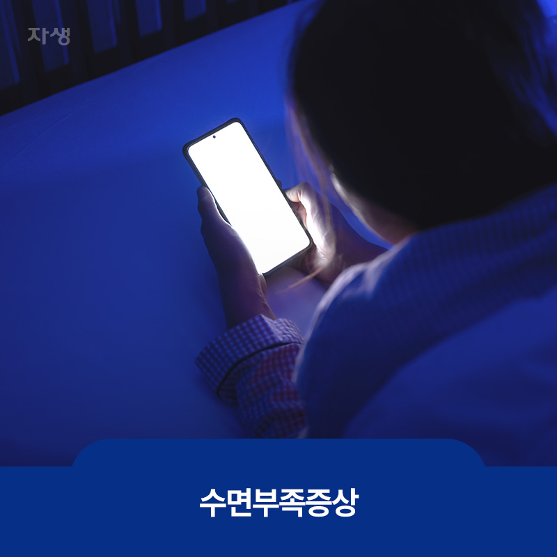 캄캄한 방에서 엎드려 휴대폰을 보고 있는 모습