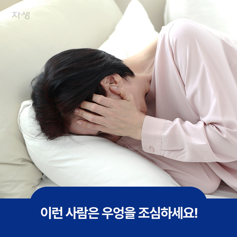 베개 위에 머리를 뭍고 양 손으로 머리를 감싸며 괴로워하고 있는 남자의 이미지