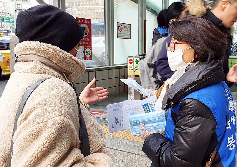 강남자생봉사단원이 시민에게 마스크를 전달하고 신종 코로나바이러스 감염증 예방법을 설명하고 있다