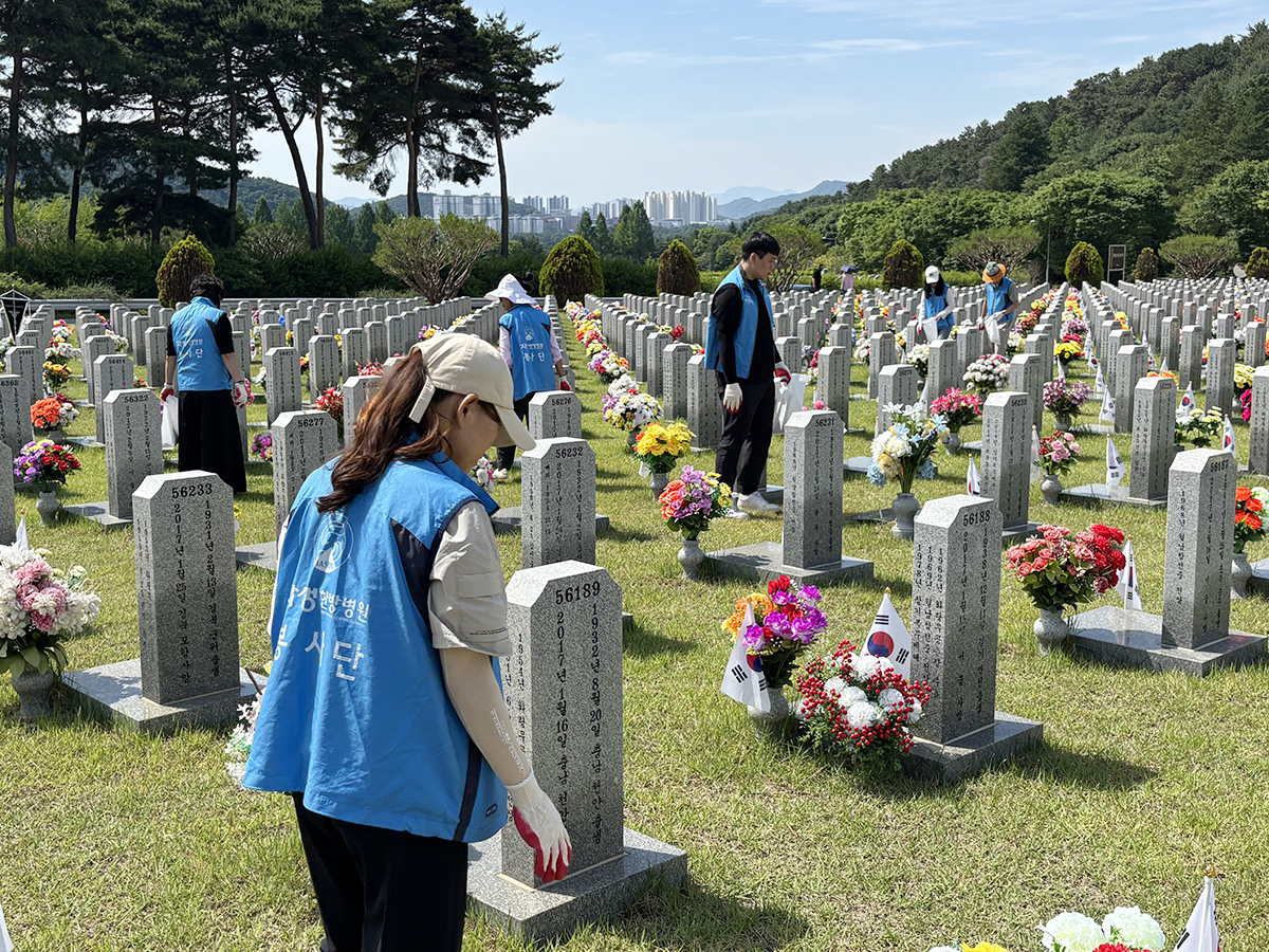 대전자생한방병원 임직원과 대전자생봉사단원들이 국립대전현충원 묘역에서 비석을 정비하고 태극기를 꽂고 있다. | 자생한방병원・자생의료재단