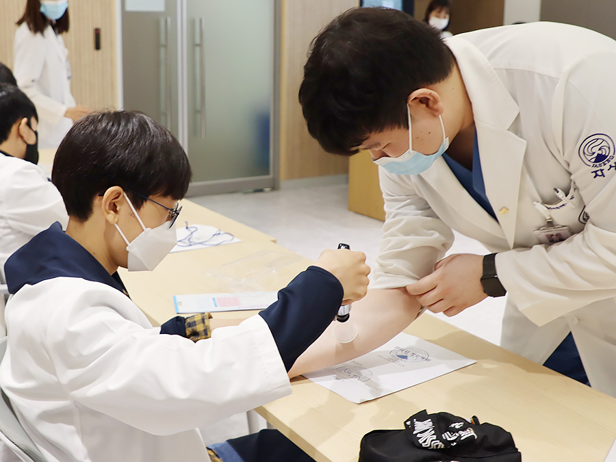 청담중학교 학생이 자생한방병원 의료진과 함께 부항치료 실습을 하고 있다. | 자생한방병원・자생의료재단