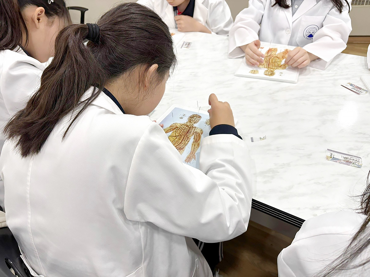 구룡중학교 학생들이 한의사 가운을 입고 침 치료 체험을 하고 있다 | 자생한방병원・자생의료재단