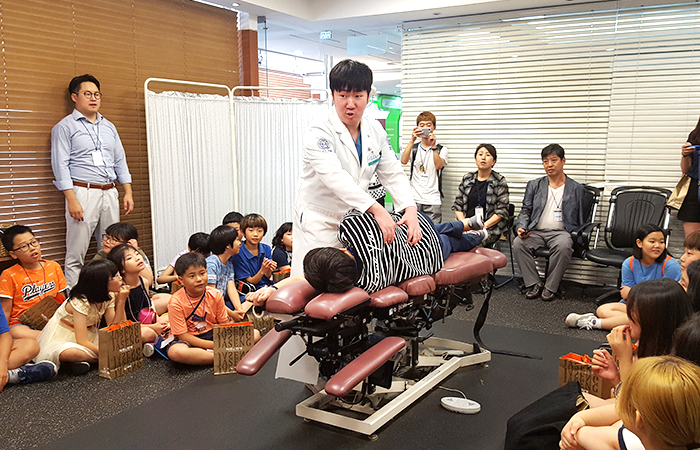 지난 1일 자생한방병원을 찾은 아동과 중학생들이 추나요법 시연을 보고 있다.